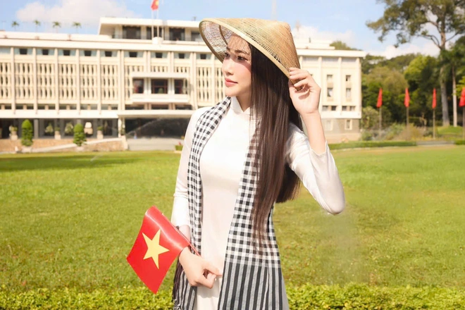 Vẻ đẹp dịu dàng của tà áo dài trắng kết hợp cùng cờ Tổ quốc tạo nên hình ảnh đầy tự hào.